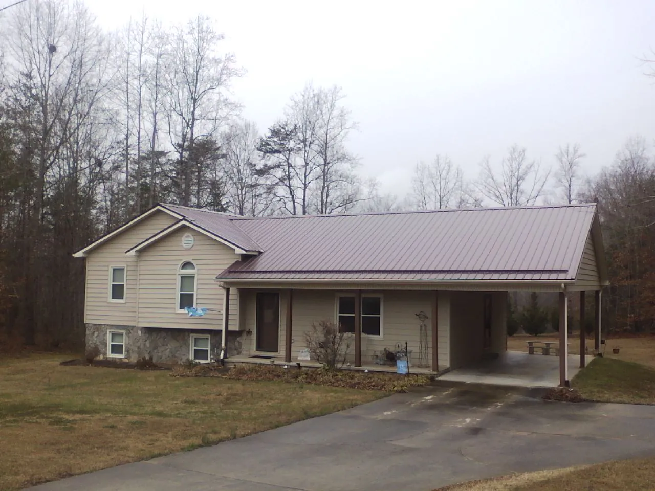 Burgundy metal roof on a tan split level home with an attached carport in Earlville