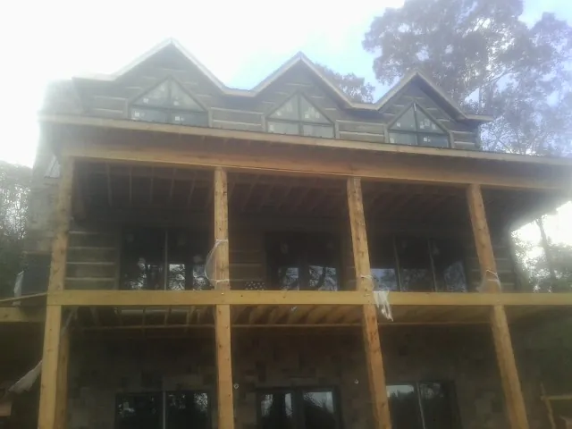 Dormers and porch framing on a large log home under construction — Roof Coating work by our crew in Earlville