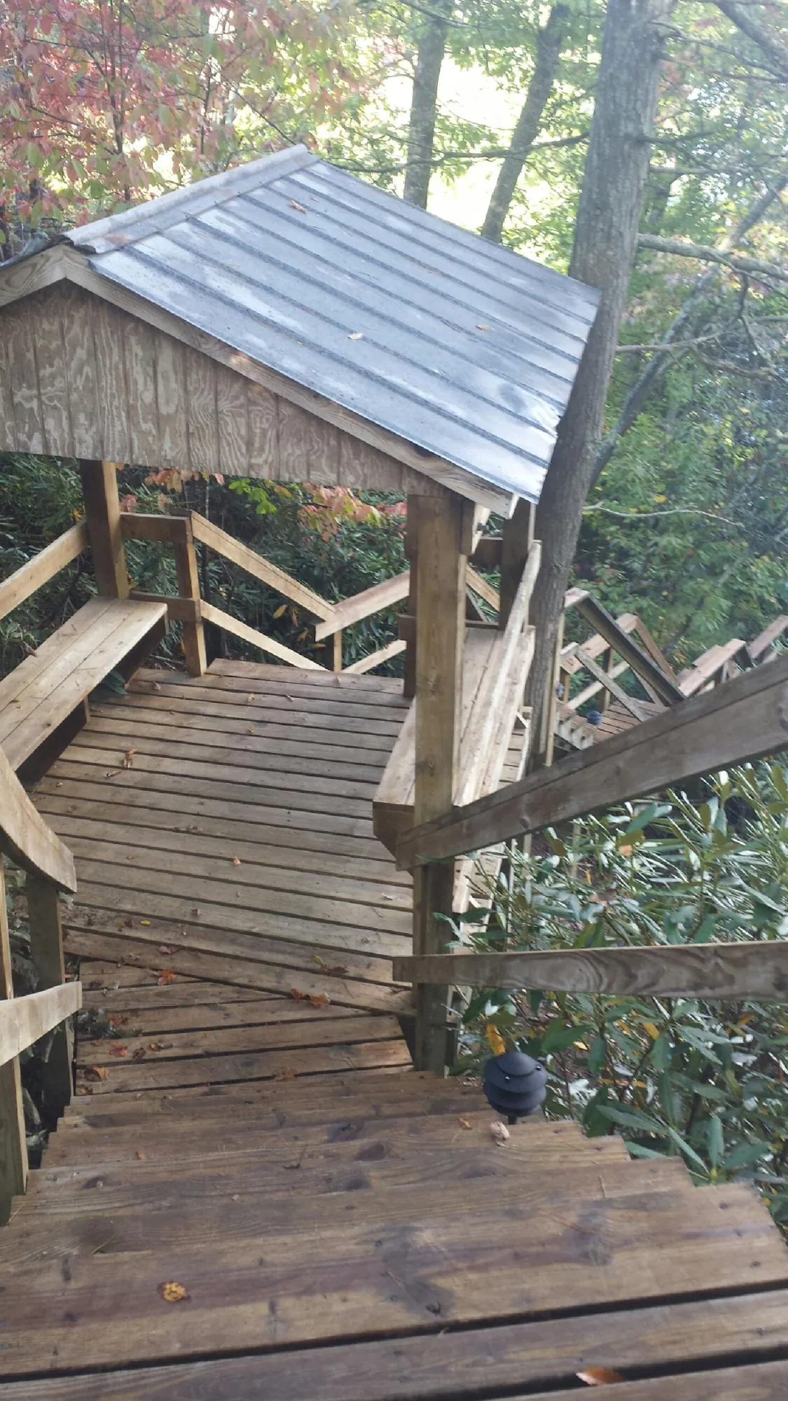 Metal roofed shelter over wooden steps on a wooded walkway — Skylight Repair & Installation work by our crew in Earlville