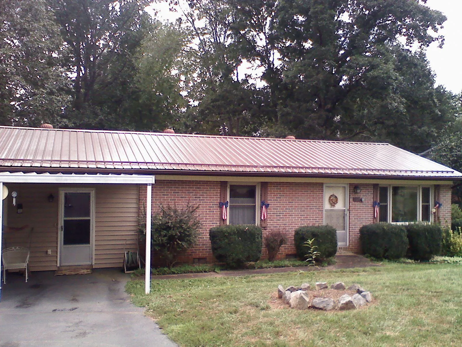 Bronze metal roof and carport on a brick ranch home — Roof Repair work by our crew in Earlville
