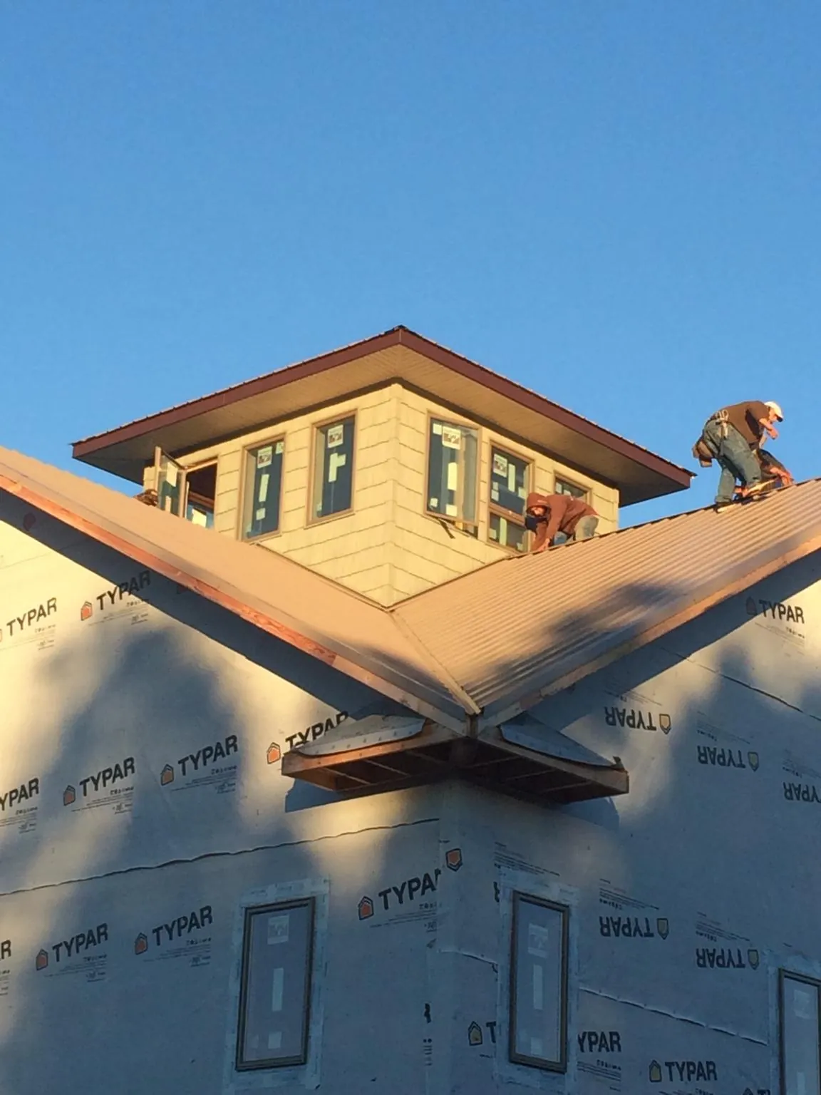 Roofers working around a rooftop cupola on a new metal roof at sunset — Roof Waterproofing in Earlville by Roofing Brothers
